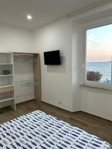 een witte kamer met een raam en een flatscreen-tv bij Stella di Mare in Civitavecchia
