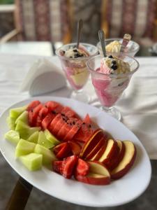 einen Obstteller auf einem Tisch mit zwei Desserts in der Unterkunft Esmeralda Butik Hotel in Kızılot
