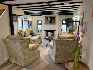 a living room with three couches and a fireplace at Huntspill Cottage in Lincolnshire