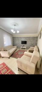 a living room with couches and a flat screen tv at Geyikli Ada Apart Otel in Geyikli