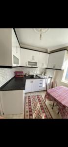 a kitchen with white cabinets and a table with a rug at Geyikli Ada Apart Otel in Geyikli