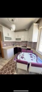 uma cozinha com uma mesa e algumas cadeiras roxas em Geyikli Ada Apart Otel em Geyikli