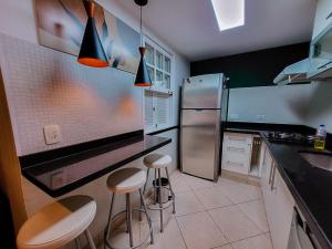 a kitchen with a refrigerator and two stools in it at Casa Vila da Praia Buzios - Centro in Búzios