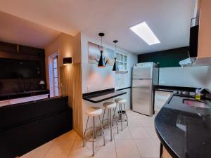 布希奧斯的住宿－Casa Vila da Praia Buzios - Centro，厨房配有吧台凳和不锈钢冰箱