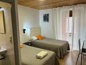 a bedroom with two beds and a bathroom with a sink at Hostal ARS in Puigcerdà