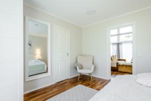 um quarto branco com uma cadeira branca e um espelho em Haagi-Villa em Herjava