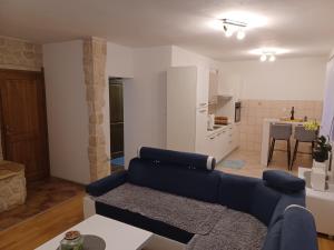 a living room with a blue couch and a kitchen at Apartmani Marijamagdalena in Gračac