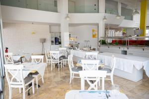 a restaurant with white tables and chairs and a kitchen at Napa Jay Hotel in Ayia Napa