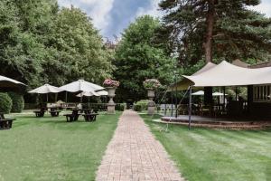 un jardín con mesas y sombrillas en el césped en Ye Olde Bell Hotel & Spa, en Retford