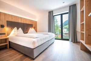 een slaapkamer met een groot bed en een groot raam bij Apartments LaBar in Ortisei
