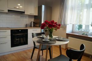 a kitchen with a table with a vase of red flowers at Apartament Ostoya 2 w centrum Ełku in Ełk
