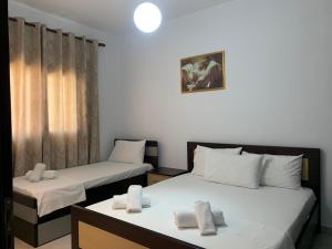 um quarto com duas camas com lençóis brancos em Guesthouse Jasmine em Ksamil