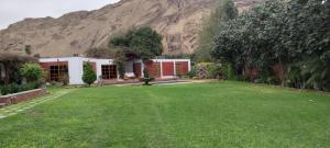 a house with a large lawn in front of a mountain at Las buganvilias in Pachacamac