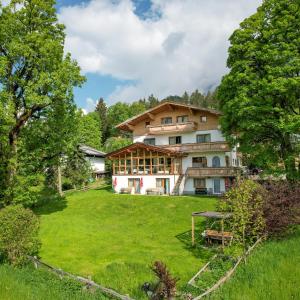 a large house in the middle of a green field at Pension Hofweyer in Ramsau am Dachstein