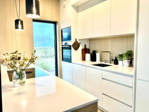 a kitchen with white cabinets and a vase of flowers on a counter at New luxury cabin near Henningsvær Lofoten in Kleppstad