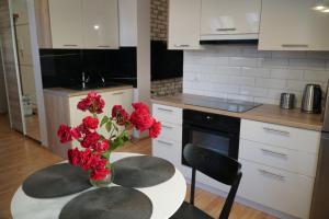 a kitchen with a table with red flowers in a vase at Apartament Ostoya 2 w centrum Ełku in Ełk