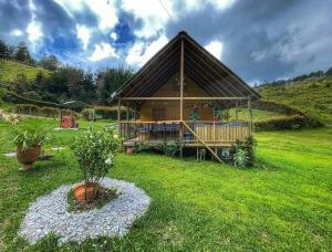 a log cabin in a grassy field with a house at Espectacular Cabaña Loft en Guatape - Jacuzzi in El Peñol