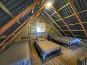 an attic room with two beds and a window at Espectacular Cabaña Loft en Guatape - Jacuzzi in El Peñol