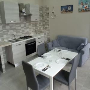een keuken met een witte tafel en stoelen en een bank bij Casa vacanze Via Treglia in Scauri