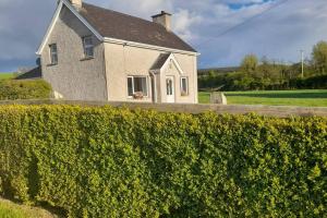 a white house with a hedge in front of it at Emma's Cottage in Brookeborough