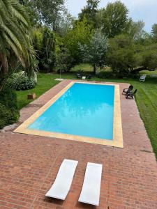 una piscina con 2 tumbonas junto a ella en Don Aniceto Lodges & Glamping en Luján