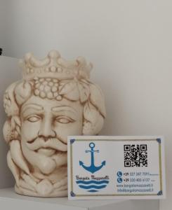 Una statua di una testa con una corona e un segno di Borgata Mazzarelli a Marina di Ragusa