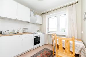 a kitchen with white cabinets and a wooden chair at Merevaatega kesklinna korter in Haapsalu