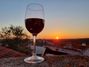 um copo de vinho sentado numa saliência com o pôr-do-sol em Casa da Avó Mirinha em Figueira e Barros