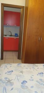 Zimmer mit einem Bett und einer Küche mit roten Schränken in der Unterkunft La Casa di Lola in Alcamo