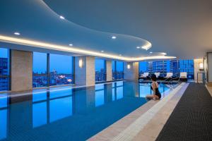 a woman sitting next to a swimming pool in a building at Courtyard by Marriott Suzhou in Suzhou