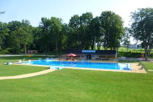 una gran piscina en un parque con un edificio en Penzion a vinařství NATURVINI en Miroslav