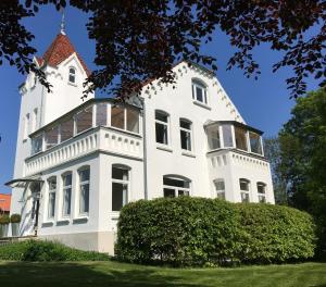 a large white house with a red roof at Villa Baltica - Wintergarten-Appartement in Schönberg in Holstein