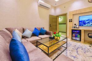a living room with a couch and a tv at Wissam Al-Hawra Hotel in Umm Lujj