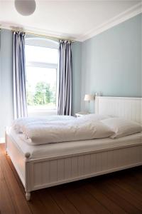 a bedroom with a large white bed with a window at Villa Baltica - Wintergarten-Appartement in Schönberg in Holstein