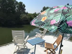 - une terrasse avec des chaises et un parasol à côté de l'eau dans l'établissement Péniche Match, à Arles