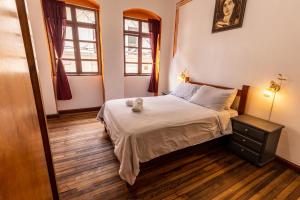 a small bedroom with a bed and two windows at Vibes Aurik in Quito