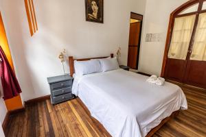 a bedroom with a white bed with a nightstand and a window at Vibes Aurik in Quito
