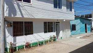 a white building with a fence next to a street at Posada Nativa Mulu in San Andrés