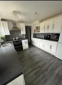 a large kitchen with white cabinets and wooden floors at The Ebs Lodge 