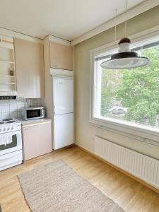 eine Küche mit einem weißen Kühlschrank und einem Fenster in der Unterkunft Woodpecker Avenue Apartment Turku in Turku