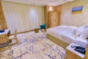 een hotelkamer met een bed, een bureau en een stoel bij Wissam Al-Hawra Hotel in Umm Lajj