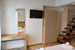 a bedroom with a tv on the wall and a closet at Dioscuri Deluxe Apartments in Chrysi Ammoudia