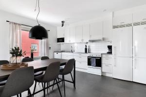 eine weiße Küche mit einem Holztisch und Stühlen in der Unterkunft Guestly Homes - 3BR Modern Apartment in Piteå