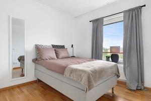 a white bedroom with a bed and a window at Guestly Homes - 3BR Modern Apartment in Piteå