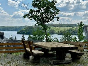 uma mesa de piquenique de madeira com dois bancos e um lago em Auszeit im Wald direkt am See em Schleiz