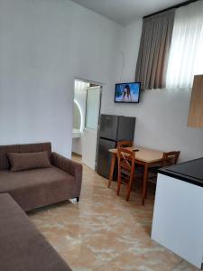 ein Wohnzimmer mit einem Sofa und einem Tisch sowie eine Küche in der Unterkunft VILA PUSHIMI REGIS in Velipojë
