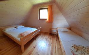 ルシノボにあるBursztynowe domkiのベッド2台付きの客室で、キャビン内に窓があります。