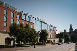 un grande edificio in vetro su una strada di città alberata di Sheraton Grand Krakow a Cracovia