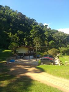 a house with a car parked in front of a mountain at Fazenda Piloes in Itaipava