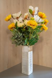 un jarrón lleno de flores amarillas y blancas en una mesa en Bed&Breakfast Novalis, en Novalja